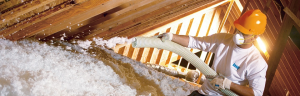 A man installing blown-in insulation in an attic
