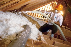 A technician installing blown-in insulation in an attic.