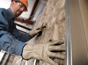 Technician installing fiberglass batt wall insulation.