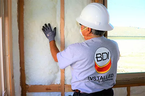 Employee inspecting fiberglass batt wall insulation